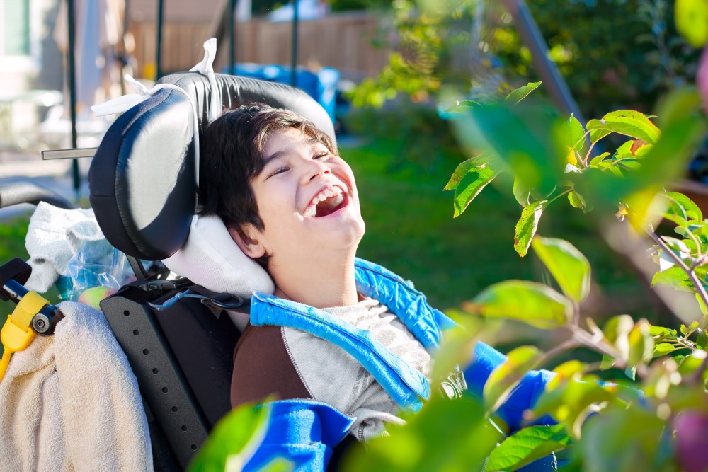 Disabled biracial ten year old boy in wheelchair relaxed and laughing in back yard